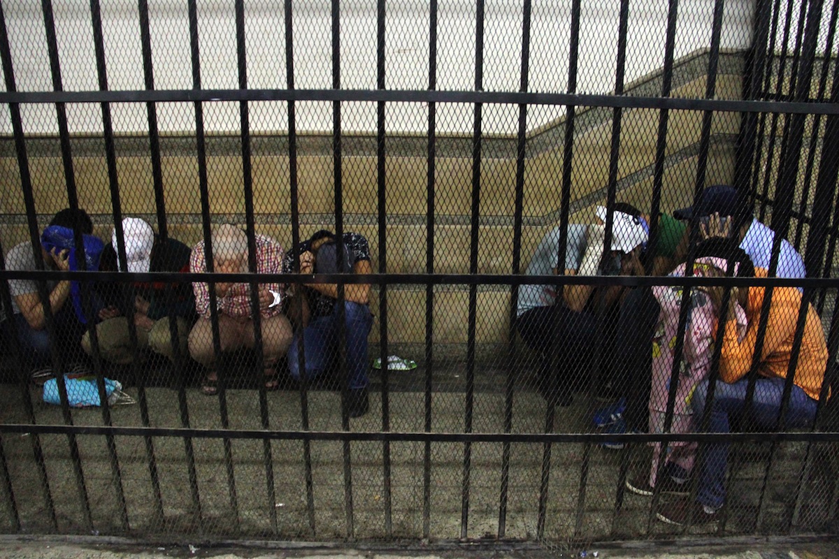 Eight Egyptian men on trial for doing a video prosecutors claimed was of a gay wedding hide their identities as they sit in the defendent's cage during their trial in Cairo on November 1, 2014. The video, filmed aboard a Nile riverboat, shows what prosecutors said was a gay wedding ceremony, with two men in the centre kissing, exchanging rings and cutting a cake with their picture on it. The Egyptian court jailed the eight men for three years. AFP PHOTO / STR