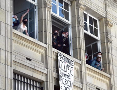 Students gestures in front of a banner reading "the Sorbonne occupied against Macron and Le Pen and their world" at the Sorbonne University in Paris on April 14, 2022,  as they stage a protest ten days ahead of the second round of France's presidentialele election. - Several hundred students mobilised on April 14, 2022 in Paris and Nancy, blocking university buildings to make their voices heard between the two rounds of the presidential election and to raise awareness of ecological and social issues. (Photo by EMMANUEL DUNAND / AFP)