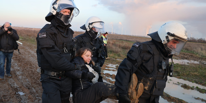dpatop - 17 January 2023, North Rhine-Westphalia, Erkelenz: Police officers carry Swedish climate activist Greta Thunberg (M) out of a group of protesters and activists and away from the edge of the Garzweiler II opencast lignite mine. Activists and coal opponents continue their protests at several locations in North Rhine-Westphalia on Tuesday. Photo: Christoph Reichwein/dpa
