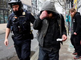 Police officer David Baer pulls a man, who was caught smoking fentanyl, to issue him a citation and to offer him a card that lists a 24-hour treatment hotline which he can call to get his citation dismissed in Portland, Oregon, U.S. February 7, 2024.  REUTERS/Deborah Bloom